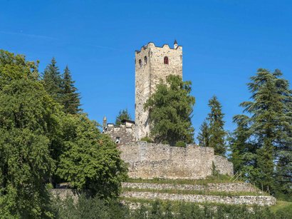 Ferragosto in Alto Adige Castello di pietra con torre su collina alberata sotto cielo blu
