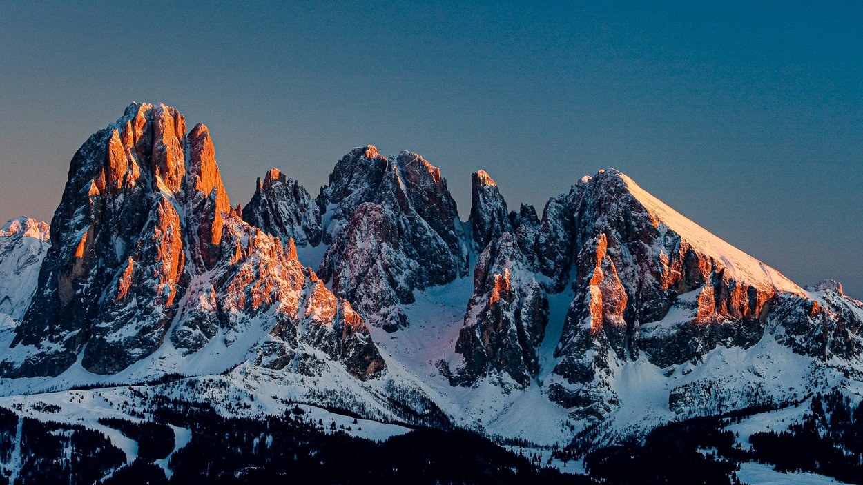 Sassolungo: un massiccio maestoso Montagne innevate al tramonto con luce arancione sulle cime