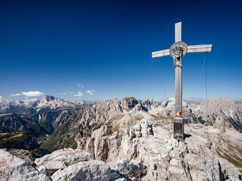 Via ferrata Monte Paterno: che spettacolo! Croce di legno con testa di Gesù sulla vetta montuosa nelle Dolomiti con cielo limpido