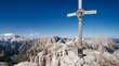 Ihre Hotels nahe der Drei Zinnen im Hochpustertal Holzkreuz mit Jesuskopf auf Berggipfel in den Dolomiten bei klarem Himmel