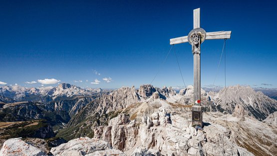 Via ferrata Monte Paterno: che spettacolo! Croce di legno con testa di Gesù sulla vetta montuosa nelle Dolomiti con cielo limpido