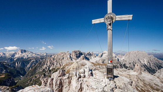 Hotel presso le Tre Cime di Lavaredo Croce di legno con testa di Gesù sulla vetta montuosa nelle Dolomiti con cielo limpido