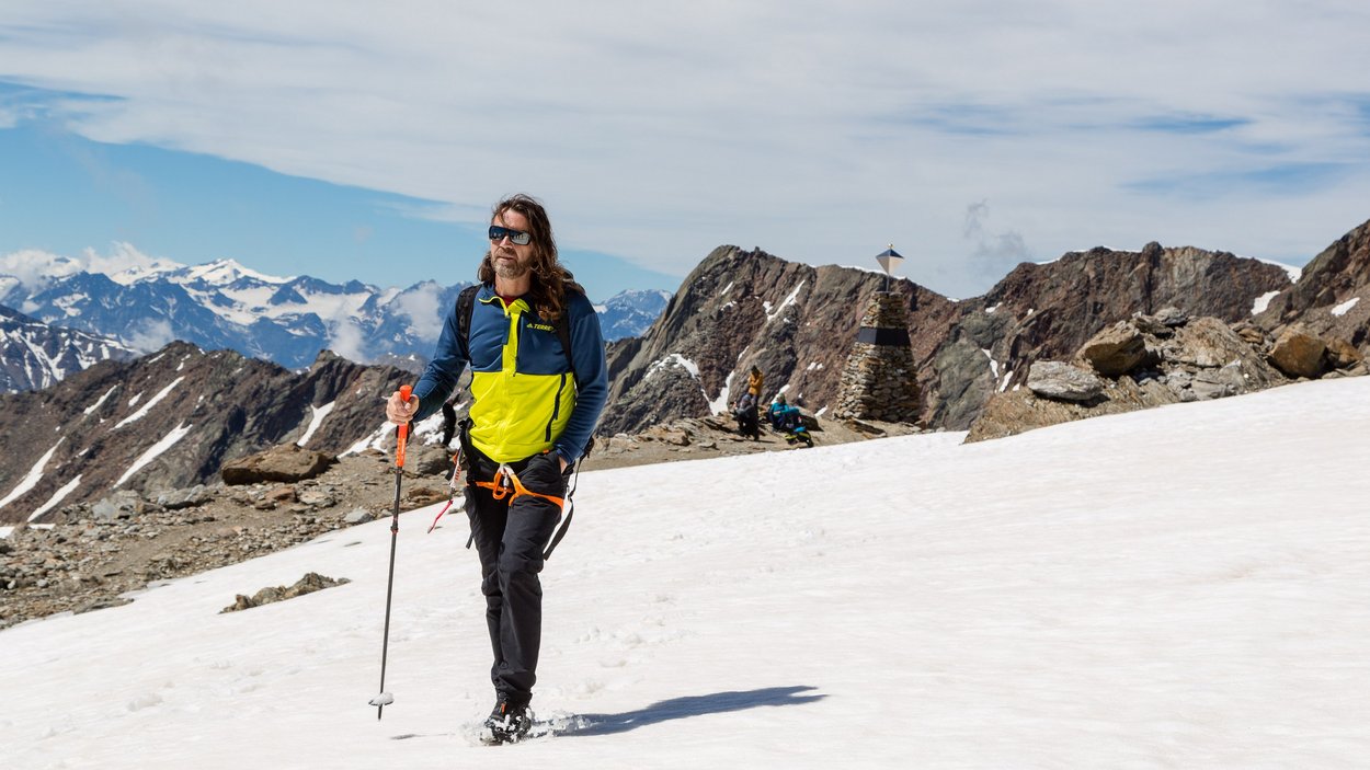 Die kuriosesten Denkmäler in Südtirol Mann wandert mit Trekkingstock auf schneebedecktem Berg im Alpinen Gebirge