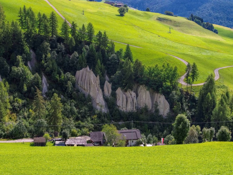 Hotels Terenten: Urlaub im Sonnendorf Grüne Wiesen mit Felshügeln und einigen Häusern im Tal