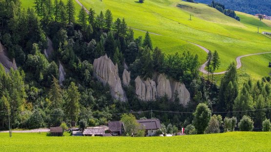 Hotels Terenten: Urlaub im Sonnendorf Grüne Wiesen mit Felshügeln und einigen Häusern im Tal