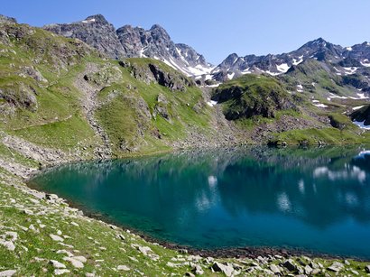 Reschensee: Naturparadies in Südtirol Bergsee mit klarem Wasser und schneebedeckten Gipfeln unter blauem Himmel
