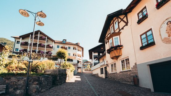Hotel a Luson in Alto Adige Strada lastricata e case tradizionali in un villaggio soleggiato
