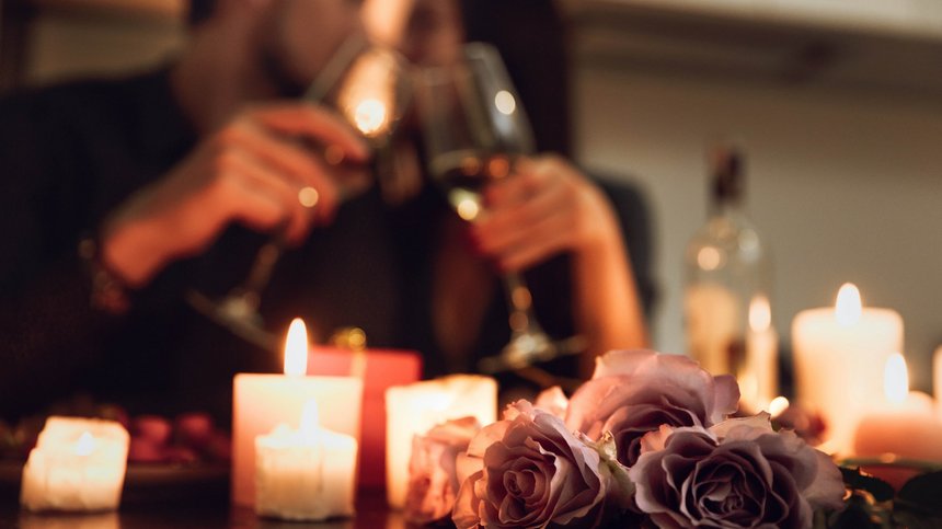 Hotel in Alto Adige 😎☀️ Per vacanze indimenticabili Cena romantica con rose, candele accese e coppia che brinda con calici di vino