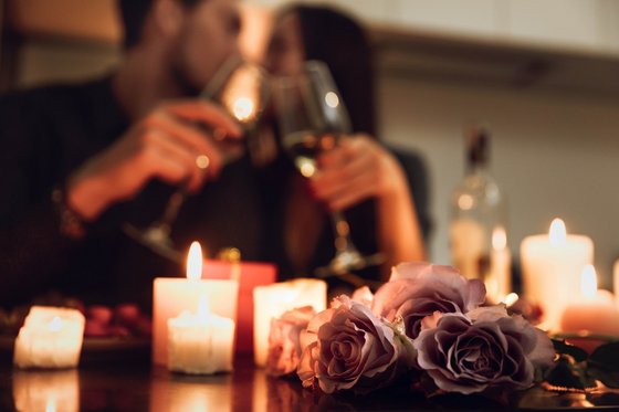Romantische Hotels Südtirol – Urlaubsträume in den Bergen Romantisches Abendessen mit Rosen, Kerzenlicht und einem Paar mit Weingläsern