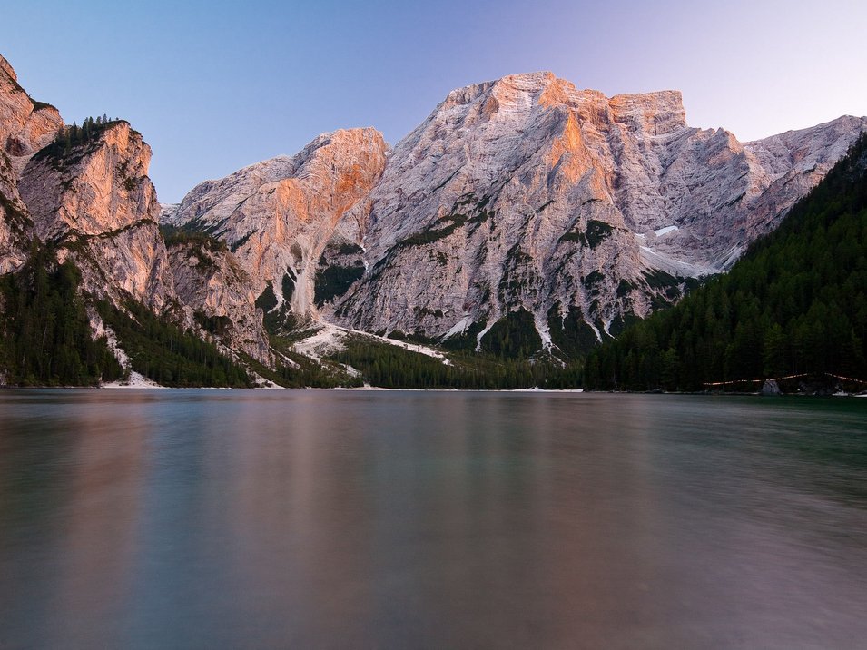 Hotels in den Dolomiten in Südtirol Berglandschaft mit See und bewaldeten Hängen bei Sonnenuntergang