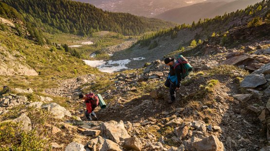 Hotels in Latsch: genau richtig für sonnige Gemüter Zwei Wanderer steigen auf einem felsigen Bergpfad bei Sonnenuntergang auf