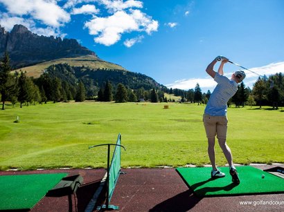 Hotel in Obereggen gesucht: Gastfreundschaft gefunden Mann beim Golfspielen auf Abschlag mit Blick auf Berge und grünes Tal