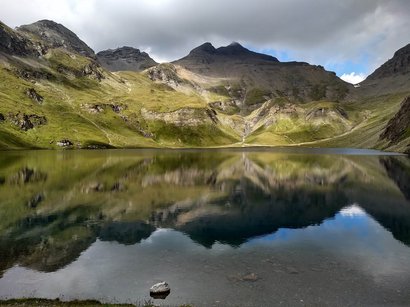Von Südtirol nach Österreich über den Wilden Freiger Berglandschaft mit See und Spiegelung unter bewölktem Himmel
