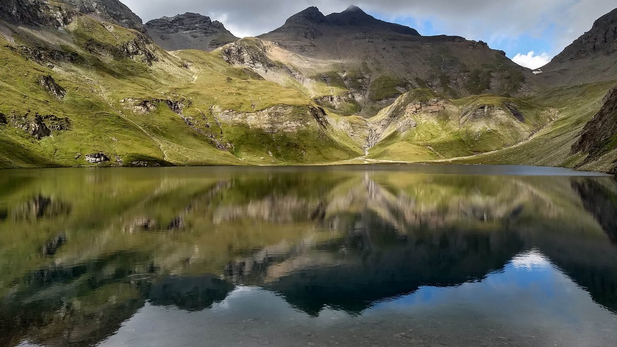 Ein Berg, zwei Gipfel Berglandschaft mit See und Spiegelung unter bewölktem Himmel