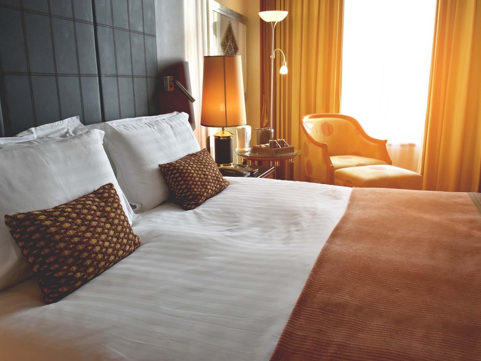 3-Sterne-Hotel in Südtirol gesucht? Gefunden! Gemütliches Hotelzimmer mit Doppelbett, Sitzsessel und warmem Licht