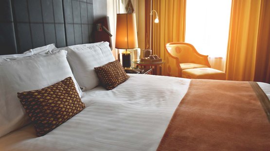 3-Sterne-Hotel in Südtirol gesucht? Gefunden! Gemütliches Hotelzimmer mit Doppelbett, Sitzsessel und warmem Licht