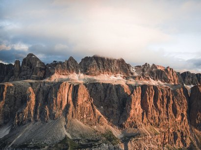 Motorradreisen durch die Dolomiten Felsen und Berge mit Wolken bei Sonnenuntergang
