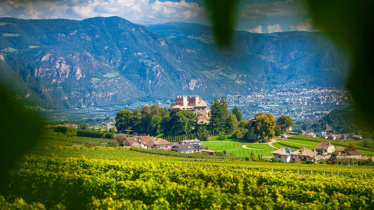 Training center ad Appiano Vista di castello e villaggio in paesaggio verde con montagne sullo sfondo