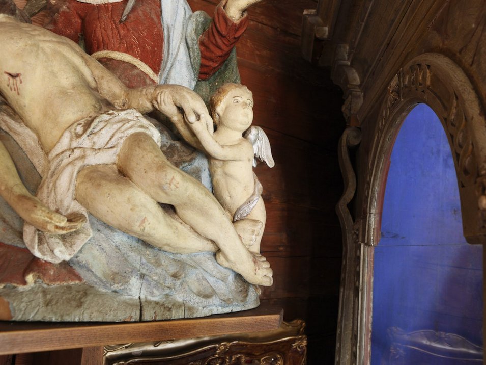 Das Ultner Talmuseum Nahaufnahme einer religiösen Statue mit Jesus und einem kleinen Engel in einem Holzraum