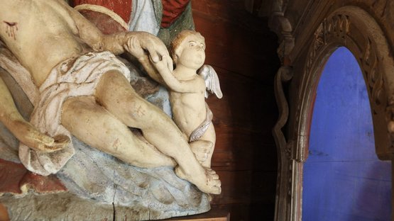 Museo della Val d‘Ultimo Primo piano di una statua religiosa con Gesù e un piccolo angelo in una stanza di legno