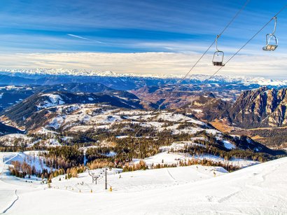 La Sellaronda, per girare attorno al massiccio del Sella Vista di montagne innevate e seggiovia sotto un cielo azzurro