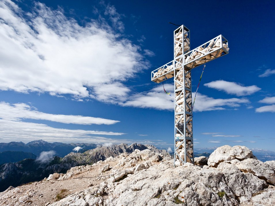 Parco naturale Sciliar-Catinaccio Croce di ferro con pietre in cima alla montagna sotto cielo blu nelle Alpi