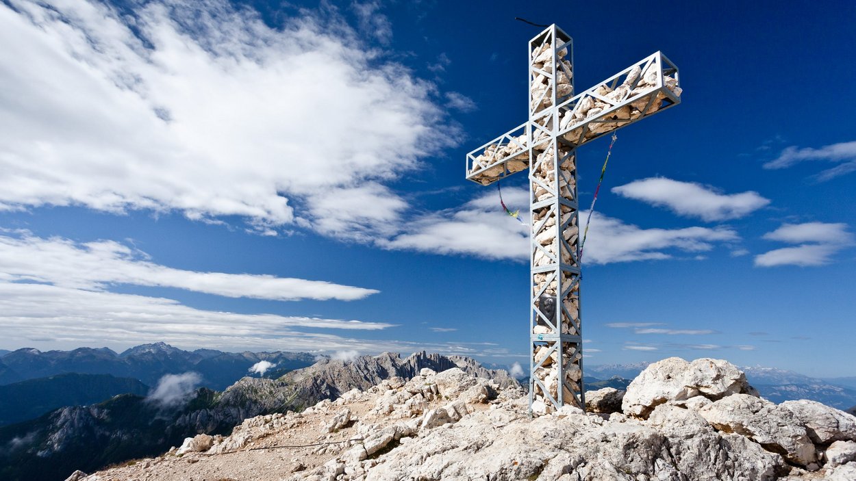 In cima al Catinaccio con la via ferrata Roda di Vael-Masarè Croce di ferro con pietre in cima alla montagna sotto cielo blu nelle Alpi
