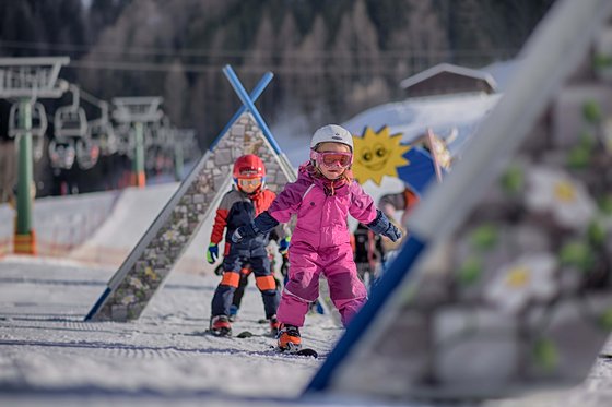 Ski-in/Ski-out in Südtirol Kinder beim Skifahren in bunten Anzügen auf einem Trainingsgelände im Schnee