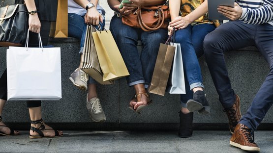Centrum Bozen Gruppe von Leuten sitzt mit Einkaufstaschen und benutzt Handy und Tablet