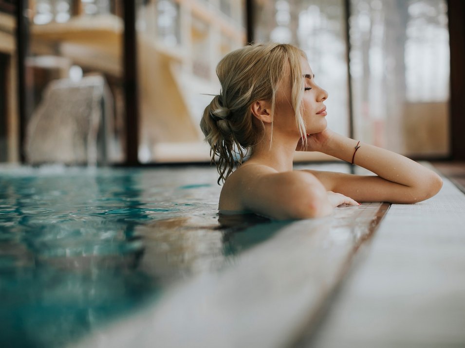 Hotel con spa in Alto Adige Una donna bionda che si rilassa al bordo di una piscina.