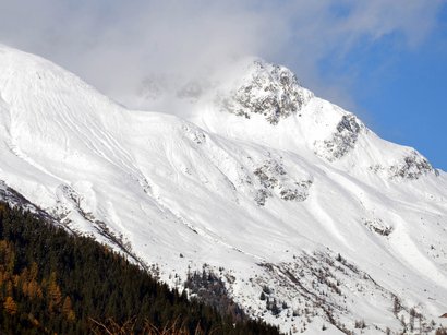 Das Skigebiet Kronplatz im Herzen der Dolomiten Verschneiter Berggipfel mit bewaldetem Hang und blauem Himmel
