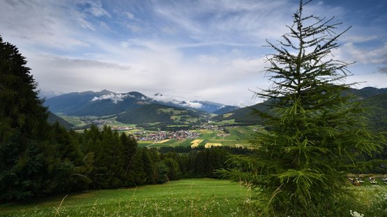 Piramidi di terra a Perca Paesaggio montano con alberi di abete e villaggio nella valle sotto un cielo nuvoloso