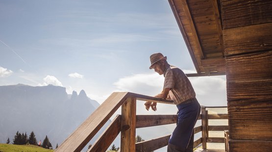 Il dialetto altoatesino Uomo anziano appoggiato a ringhiera in legno con vista sulle montagne