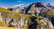 Hotels in Gröden in den Dolomiten! Berglandschaft mit grünem Gras und steilen Felsen unter blauem Himmel