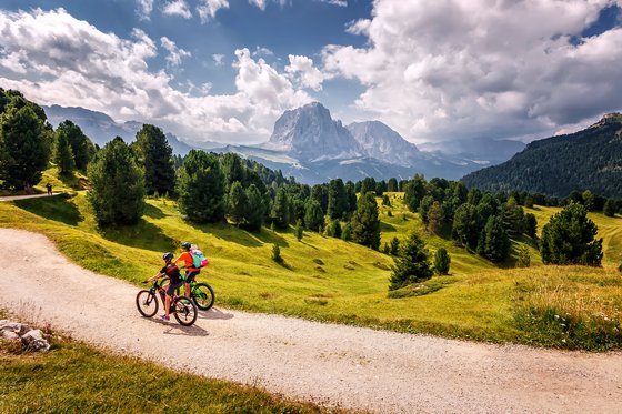 Bikehotel in den Dolomiten, im Meraner Land und, und, und Zwei Radfahrer auf einem Bergweg mit Blick auf die Dolomiten und bewölktem Himmel