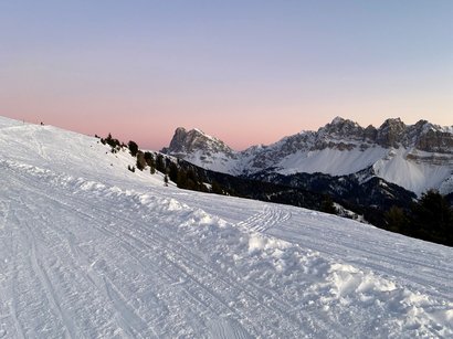 Winterwandern und Rodeln in Südtirol Verschneite Berglandschaft mit klarer Abenddämmerung und Bergen im Hintergrund