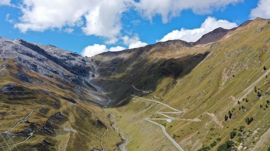 Hotels in Prad am Stilfserjoch, Natur pur in Südtirol Bergstraße mit Serpentinen zwischen grünen und felsigen Hängen unter blauem Himmel