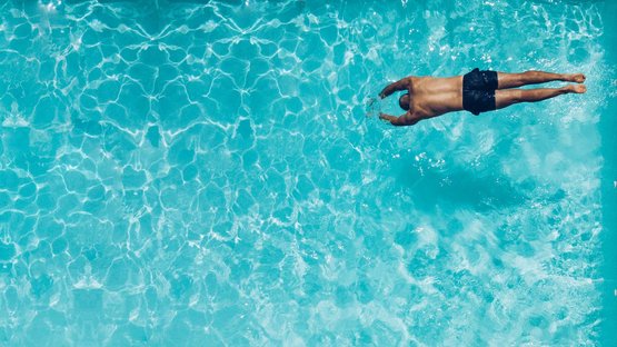 Ferienwohnungen mit Pool in Südtirol Mann taucht vorne im klaren blauen Wasser