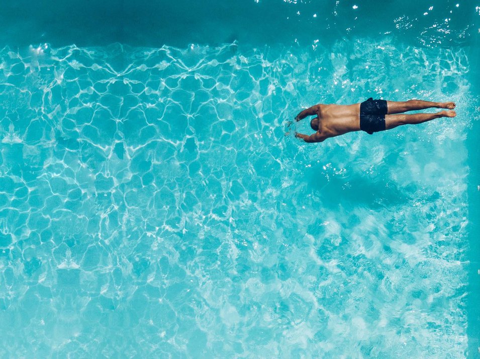 Ferienwohnungen mit Pool in Südtirol Mann taucht vorne im klaren blauen Wasser