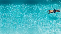 Ruster Resort Mann taucht vorne im klaren blauen Wasser