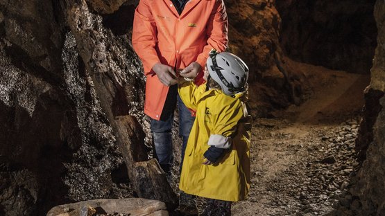 La miniera di Villandro, un pezzo di storia Adulto e bambino con caschi e giacche in una miniera con pezzi di minerale