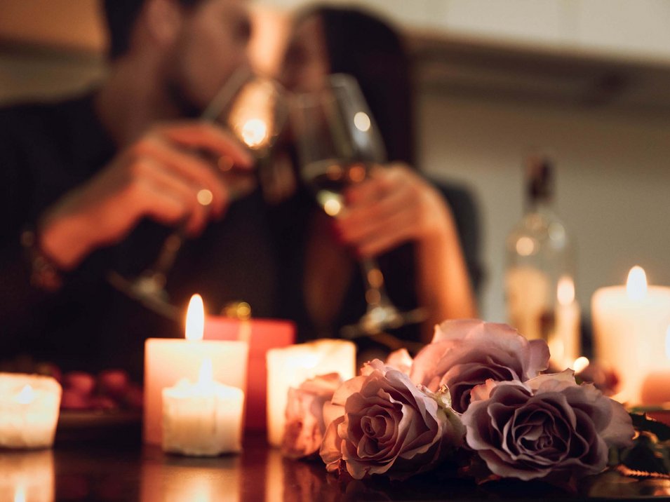 Aparthotels in Südtirol - Freiheit & Komfort Romantisches Abendessen mit Kerzenlicht, Rosen und einem Paar, das anstößt