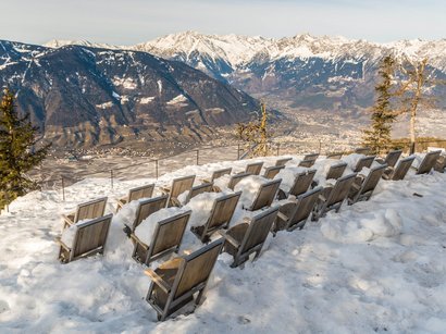 Ognissanti in Alto Adige File di sedie di legno coperte di neve su una montagna con vista sulle Alpi