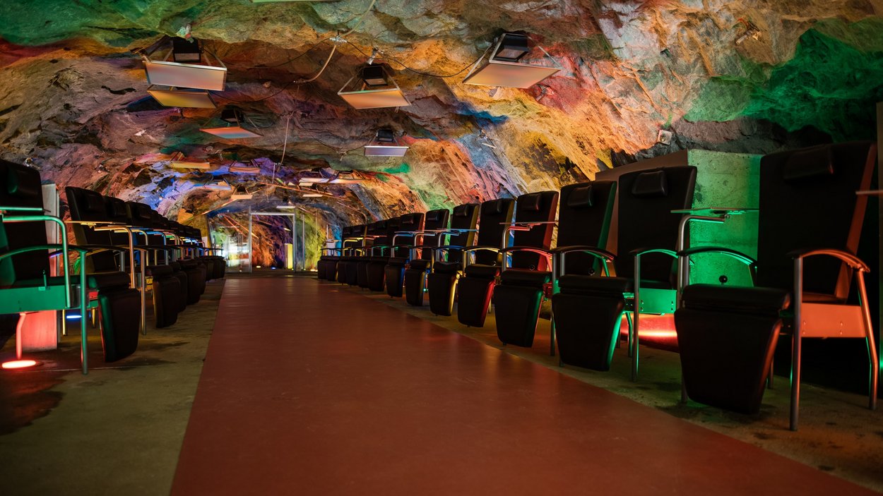 Das Bergbaumuseum in Prettau Unterirdischer Kinosaal mit bunten Lichtern und Reihen von Sitzen