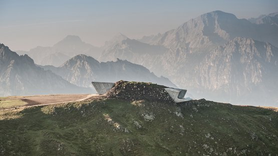 Messner Mountain Museum Piattaforma panoramica moderna su una cresta erbosa con montagne sullo sfondo