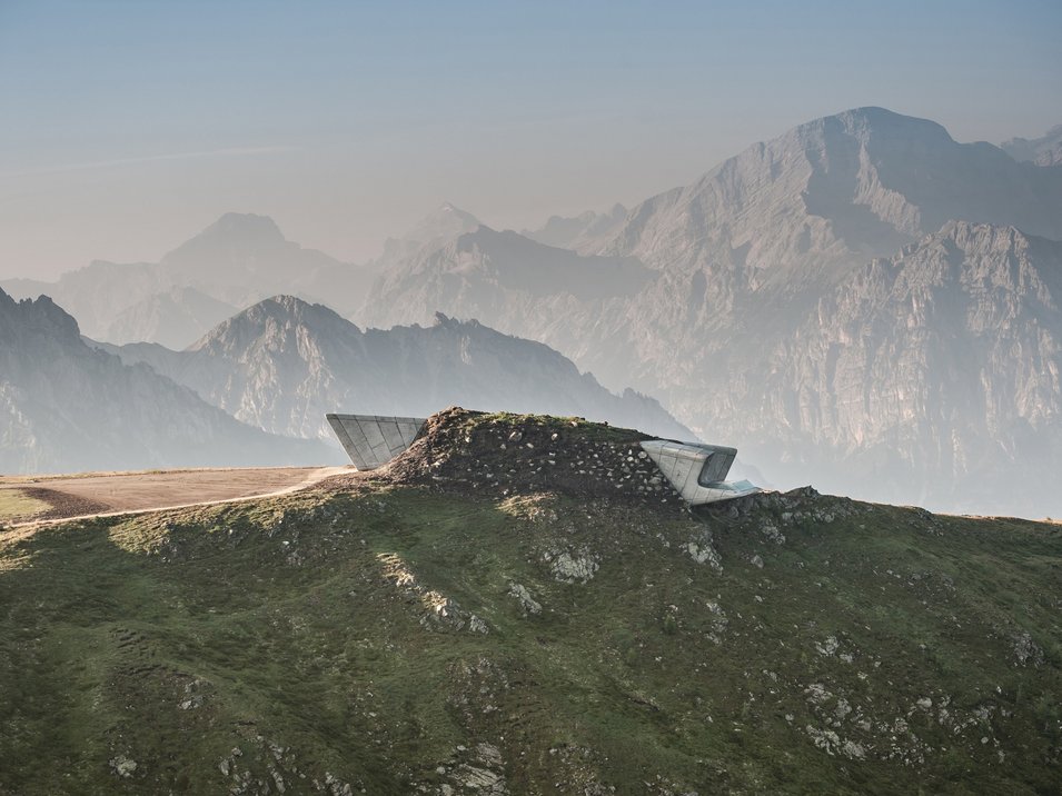 Die Messner Mountain Museen Moderne Aussichtsplattform auf einem grünen Bergrücken mit Bergen im Hintergrund