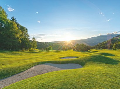 Ihre Hotels nahe der Drei Zinnen im Hochpustertal Golfplatz mit Sandbunkern bei Sonnenuntergang in hügeliger Landschaft