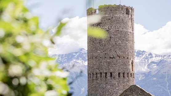 Hotels in Mals: traumhafter Urlaub in Südtirol Steinerner runder Burgturm vor Bergen und bewölktem Himmel