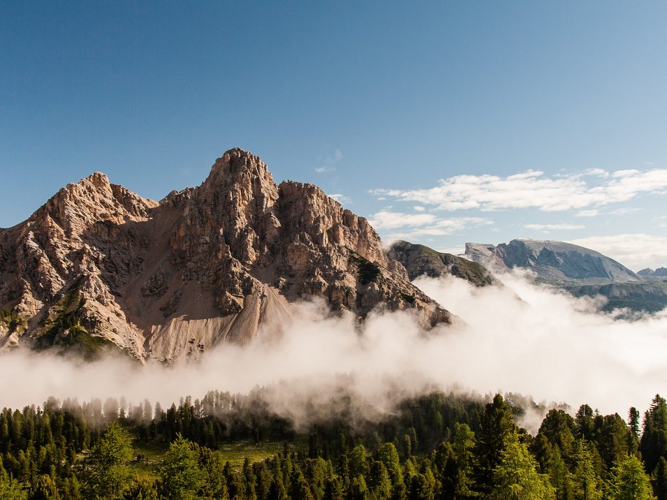 Wandern im Naturpark Fanes-Sennes-Prags Berglandschaft mit wolkenverhülltem Wald unter klarem blauen Himmel